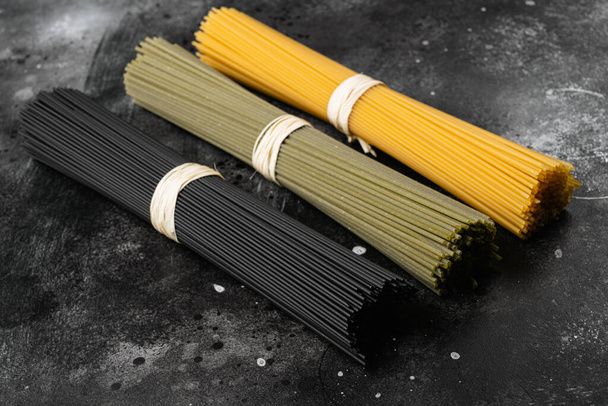 Trockene bunte Pasta-Spaghetti-Set, auf schwarzem dunklem Steintischhintergrund - Foto, Bild