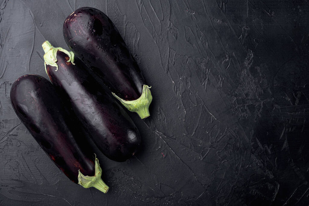 Ensemble d'aubergines biologiques fraîches, sur fond de pierre noire, vue de dessus à plat, avec espace de copie pour le texte - Photo, image