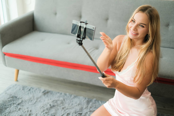 sexy femme caucasienne tenant selfie bâton avec téléphone intelligent - Photo, image