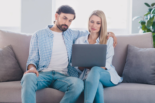 Photo of dream married couple sit couch enjoy netbook movie wear casual outfit in comfortable home indoors - Foto, afbeelding