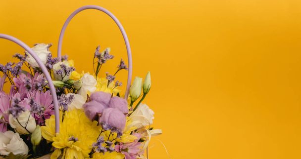 Sarı-menekşe çiçek aranjmanı bir kutu kasımpatı, Eustoma, pamuk cilt bakımı ve sarı arka planda kurumuş çiçekler. - Fotoğraf, Görsel