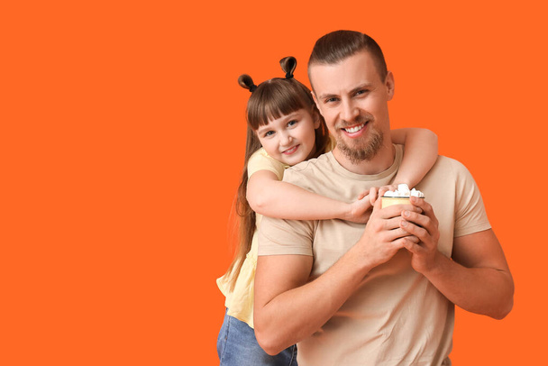Happy daughter and father with cup of hot cocoa on color background - Φωτογραφία, εικόνα