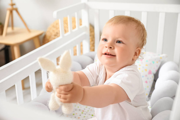 Adorable little baby with toy in crib - Foto, afbeelding