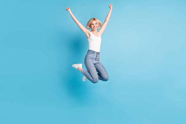 Full size portrait of delighted cheerful person hands fists up beaming smile isolated on blue color background - Valokuva, kuva