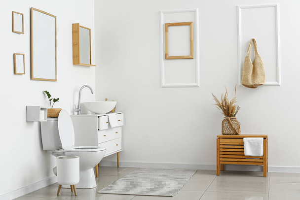 Interior of light restroom with toilet bowl and chest of drawers - Фото, изображение