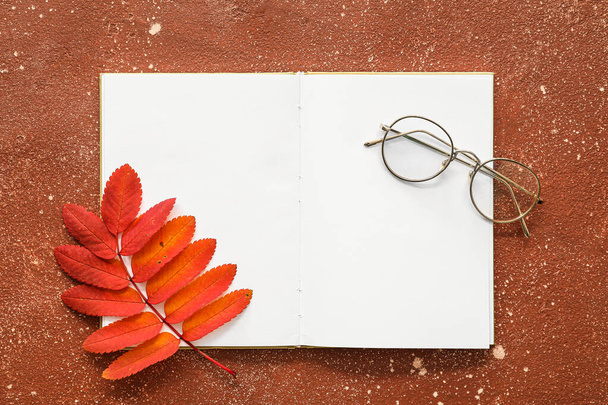 Opened book with blank pages, eyeglasses and branch with autumn leaves on color background - Φωτογραφία, εικόνα