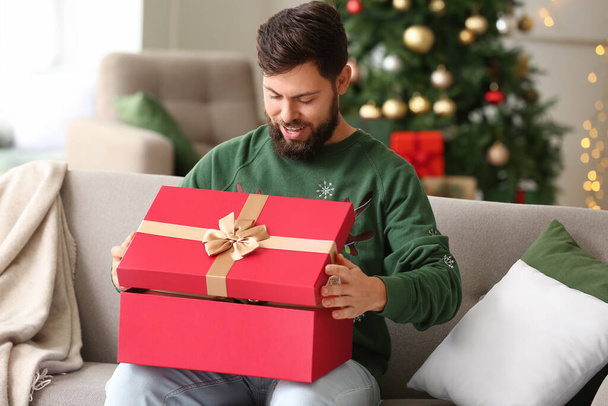 Ευτυχισμένος άνθρωπος άνοιγμα χριστουγεννιάτικο δώρο στο σπίτι - Φωτογραφία, εικόνα