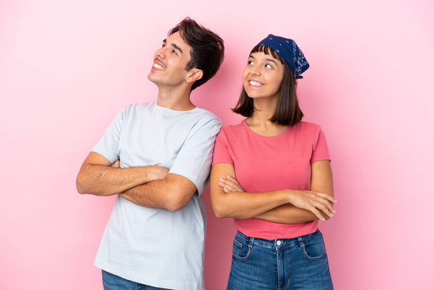 Young couple isolated on pink background looking up while smiling - Photo, Image