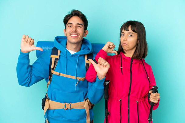 Young mountaineers couple isolated on blue background proud and self-satisfied in love yourself concept - Photo, Image