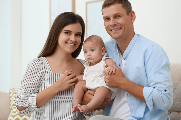 Portrait of happy family with their cute baby at home - Photo, image