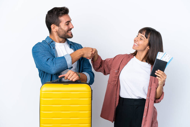 Jeune couple de voyageurs tenant une valise et un passeport isolé sur fond blanc poignée de main après une bonne affaire - Photo, image