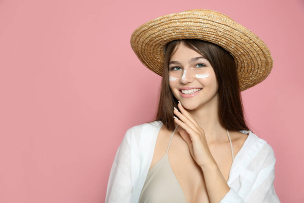 Teenage girl with sun protection cream on her face against pink background. Space for text - Fotó, kép