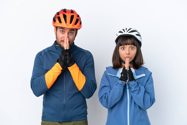 Young cyclist couple isolated on white background keeps palm together. Person asks for something - Fotó, kép