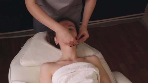 Mulher massagista terapeuta amassar saudável massagem facial cabeça relaxante terapia profissional mãos óleo. Menina deitado sofá mesa descansando fica rubdown spa salão conceito de cuidados com o corpo, tratamento em câmera lenta - Filmagem, Vídeo
