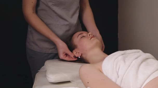 Mujer masajista terapeuta amasar la cabeza sana masaje facial relajante terapia profesional manos aceite. Chica tumbada mesa de centro de descanso se frota concepto de cuidado corporal salón de spa, tratamiento de cámara lenta - Imágenes, Vídeo