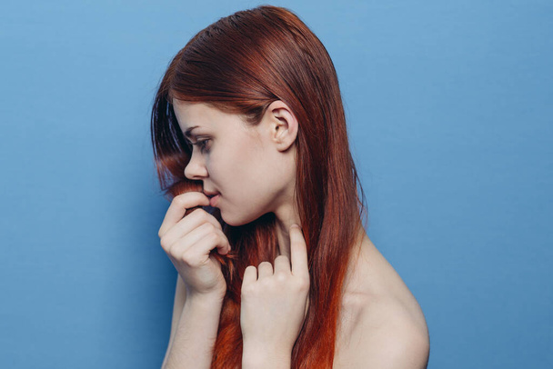 attractive woman with bare shoulders red hair close-up blue background - Valokuva, kuva