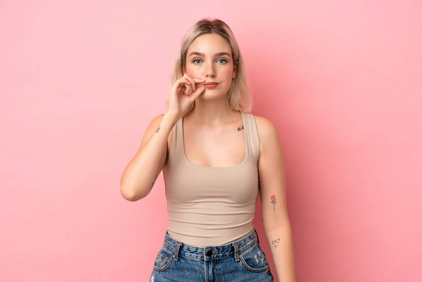 Young caucasian woman isolated on pink background showing a sign of silence gesture - Photo, image