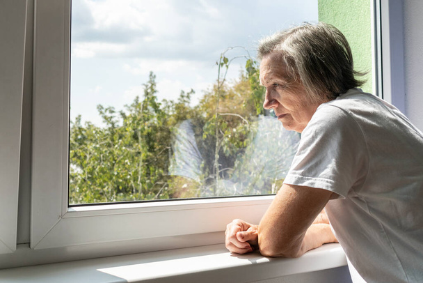 surullinen vanhempi nainen yksin pysyä kotona sisällä lähikuva masentunut coronavirus eristys leski onneton hylätty ikkuna - Valokuva, kuva