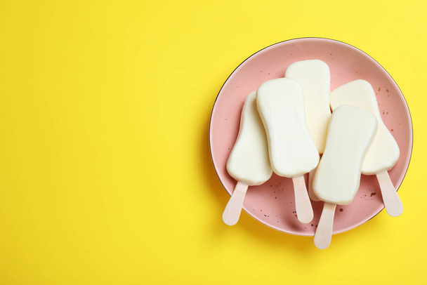 Plate with glazed ice cream bars on yellow background, top view. Space for text - Fotografie, Obrázek