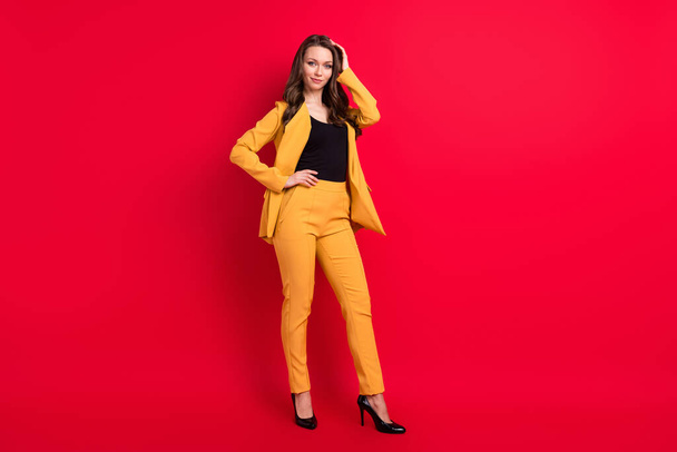 Photo of adorable shiny young woman wear yellow jacket arm waist hair smiling isolated red color background - Fotoğraf, Görsel