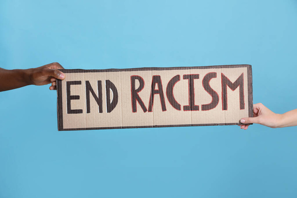Woman and African American man holding sign with phrase End Racism on light blue background, closeup - Valokuva, kuva