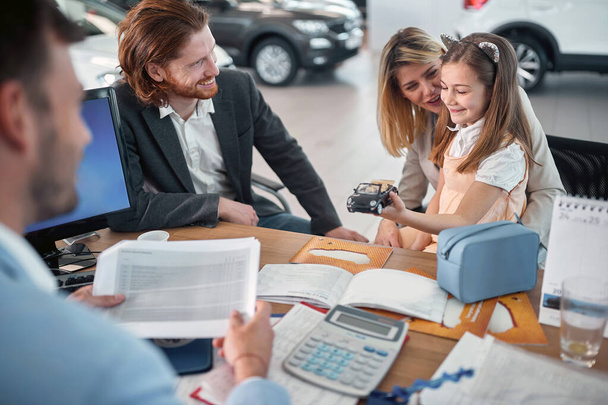 Happy family in car dealership choosing their new car - Fotografie, Obrázek