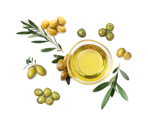 Bowl of oil, ripe olives and leaves on white background, top view - Fotó, kép