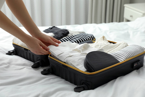 Woman packing suitcase for trip in bedroom, closeup - Fotó, kép
