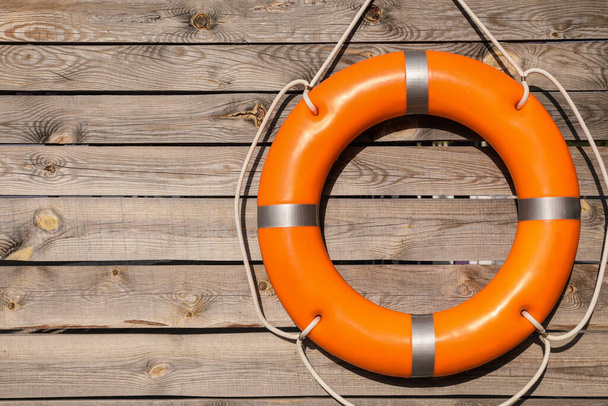Orange life buoy hanging on wooden wall, space for text - 写真・画像