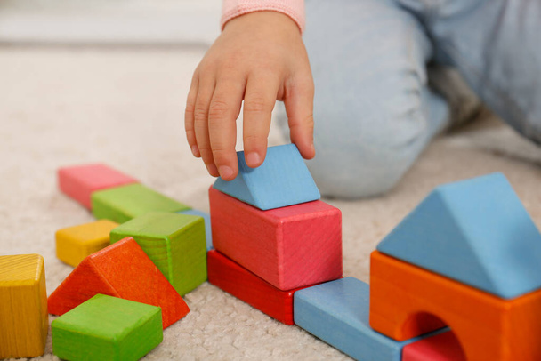 Cute little girl playing with colorful building blocks on floor, closeup - Fotoğraf, Görsel