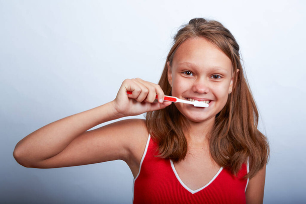 11 yaşında güzel bir kız beyaz bir arka planda dişlerini fırçalıyor. - Fotoğraf, Görsel