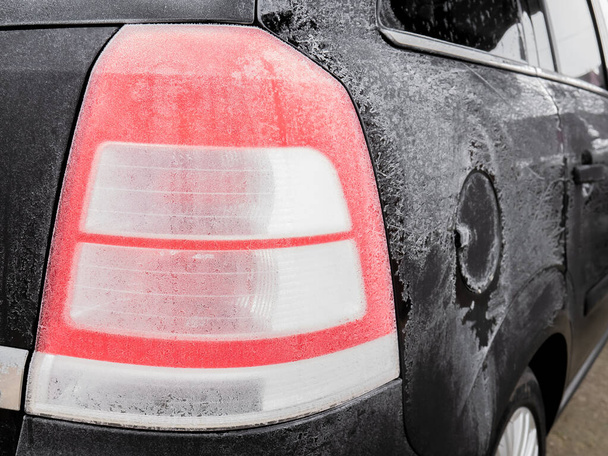 Soğuk bir kış gününde geceyi açık havada geçirdikten sonra siyah bir aracın stop lambası tamamen donmuştu. - Fotoğraf, Görsel