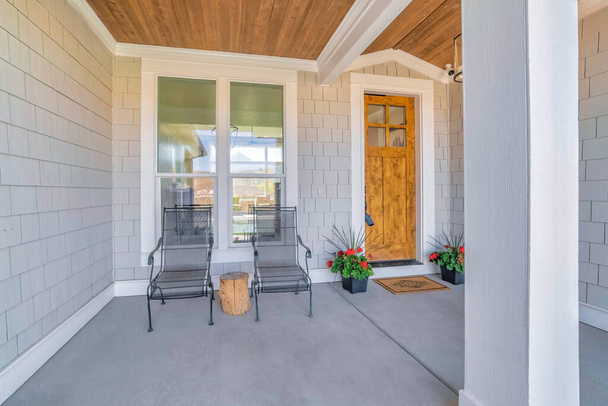 Wejście do domu z drewnianymi drzwiami frontowymi ze szklanymi szybami i roślinami doniczkowymi - Zdjęcie, obraz