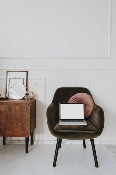 Blanco laptopsjabloon met kopieerruimte op gezellige fauteuil. Thuis werken. Modern interieur - Foto, afbeelding