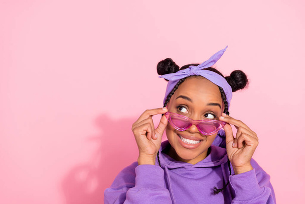 Photo of pretty attractive afro woman wear purple hoodie buns arms eyeglasses looking empty space smiling isolated pink color background - Foto, imagen