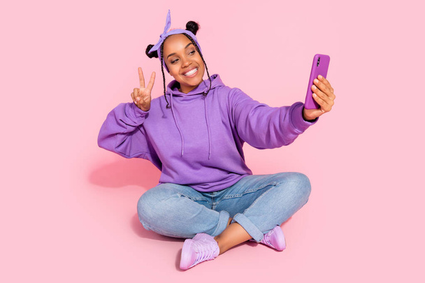 Photo of attractive beautiful lady dressed violet sweatshirt buns tacking selfie modern gadget showing v-sign isolated pink color background - Foto, imagen
