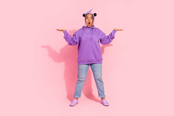 Photo of attractive beautiful afro woman wear purple hoodie buns comparing arms empty space isolated pink color background - Fotó, kép