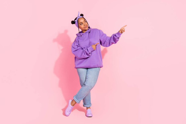 Photo of charming cute african lady dressed violet sweatshirt buns smiling pointing fingers empty space isolated pink color background - Φωτογραφία, εικόνα
