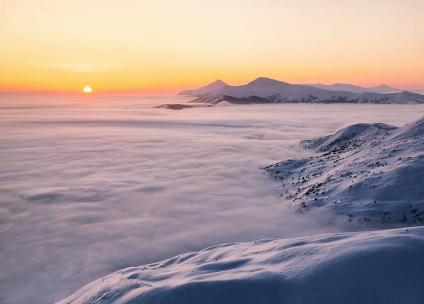 Winter. Beautiful sunrise. High mountains with snow white peaks. A panoramic view of the covered with frost trees in the snowdrifts. Natural landscape with beautiful sky. The revival of the planet. - Foto, Imagem