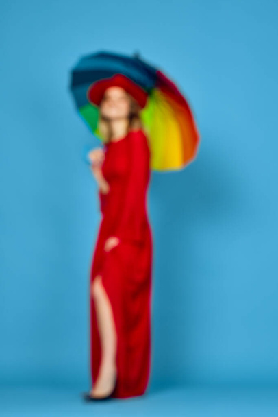 woman in red dress multicolored umbrella blue background - Foto, Imagem