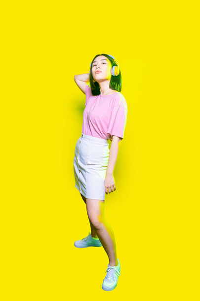 Jovem confiante mulher asiática posando usando fones de ouvido interior isolado fundo  - Foto, Imagem