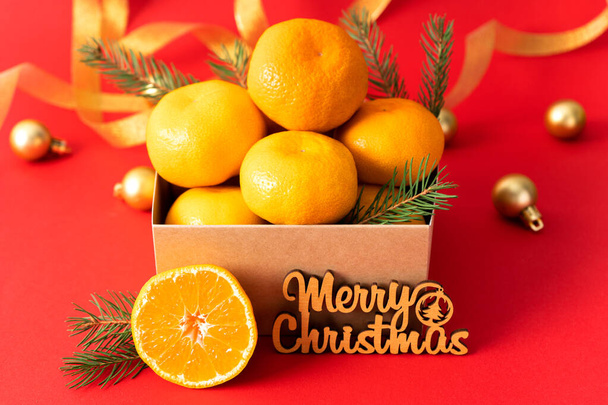 Tangerinas em uma caixa de presente em um fundo de decorações de Natal de ouro. Mandarinas de clementina suculentas frescas, frutas de tempo de inverno. Vista lateral - Foto, Imagem