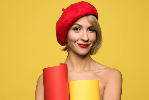 Hermosa rubia con una astuta sonrisa en un birette rojo sobre un fondo amarillo - Foto, Imagen