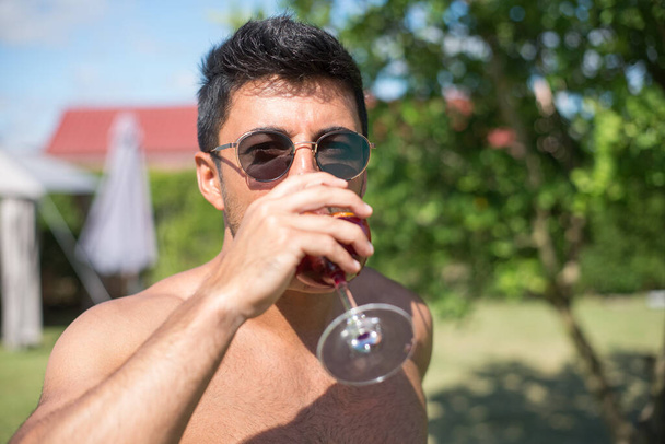 Tyylikäs nuori mies juo kirkas cocktail - Valokuva, kuva