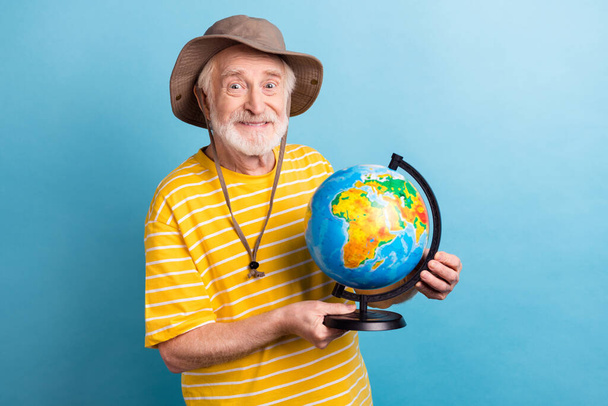Ritratto di attraente uomo allegro che tiene in mano globo continente avventura isolato su sfondo di colore blu brillante - Foto, immagini