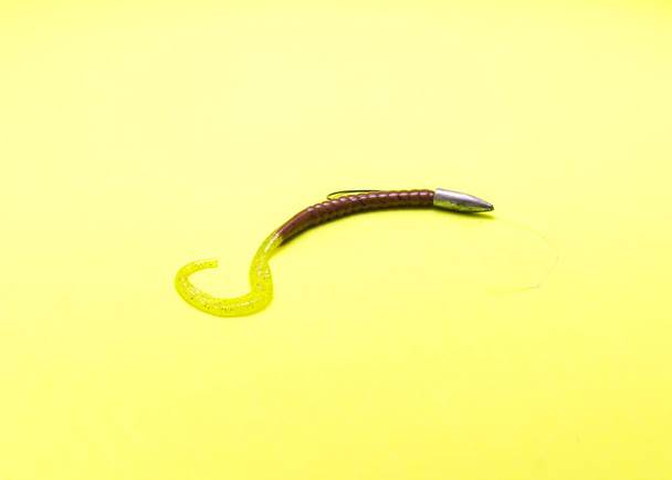 Close-up Texas tuig visserij terminal tackle met plastic worm, kogel vorm zinker en offset worm haak geïsoleerd op gele achtergrond. Gloeiende groene pompoen lokaas voor baars vissen zoetwater - Foto, afbeelding