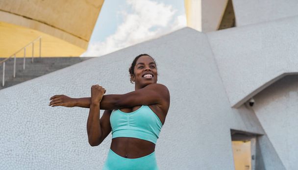Молода африканська жінка, яка займається розтягуванням перед початком тренувань у місті, займається спортивним способом життя людей. - Фото, зображення