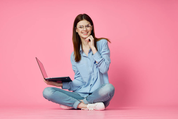 woman sitting on floor with laptop shopping entertainment pink background - Zdjęcie, obraz