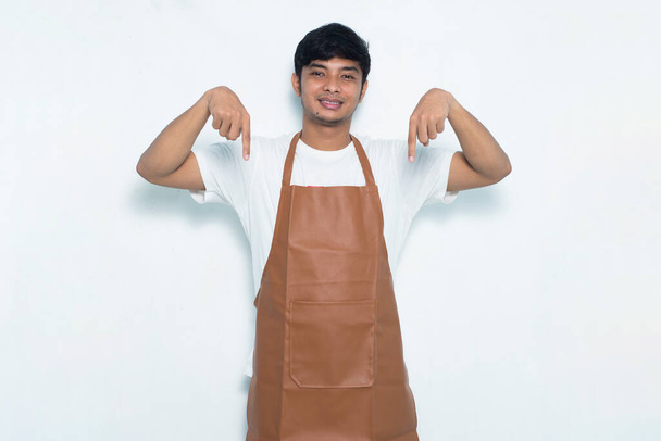 feliz joven asiático hombre barista camarera apuntando con los dedos a diferentes direcciones aislado en blanco fondo - Foto, Imagen