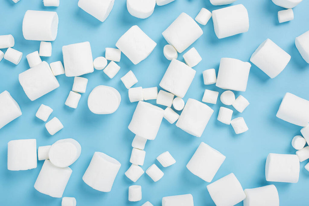Witte marshmallows op een blauwe achtergrond. Bovenaanzicht, vlak lay - Foto, afbeelding